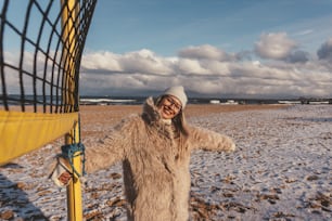 a woman standing next to a yellow net on a beach