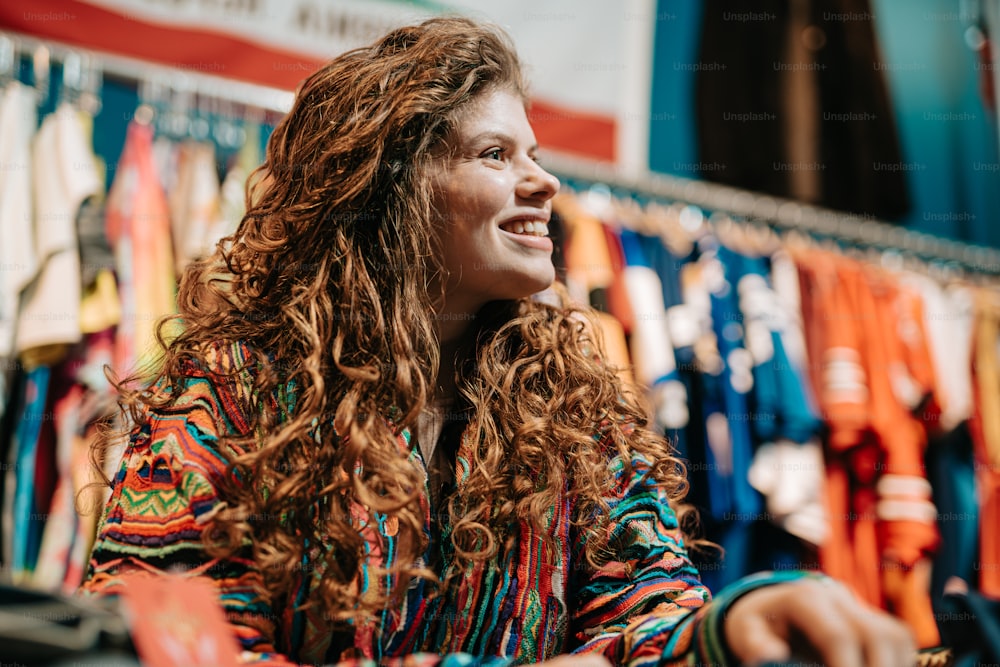 a woman sitting in front of a rack of shirts