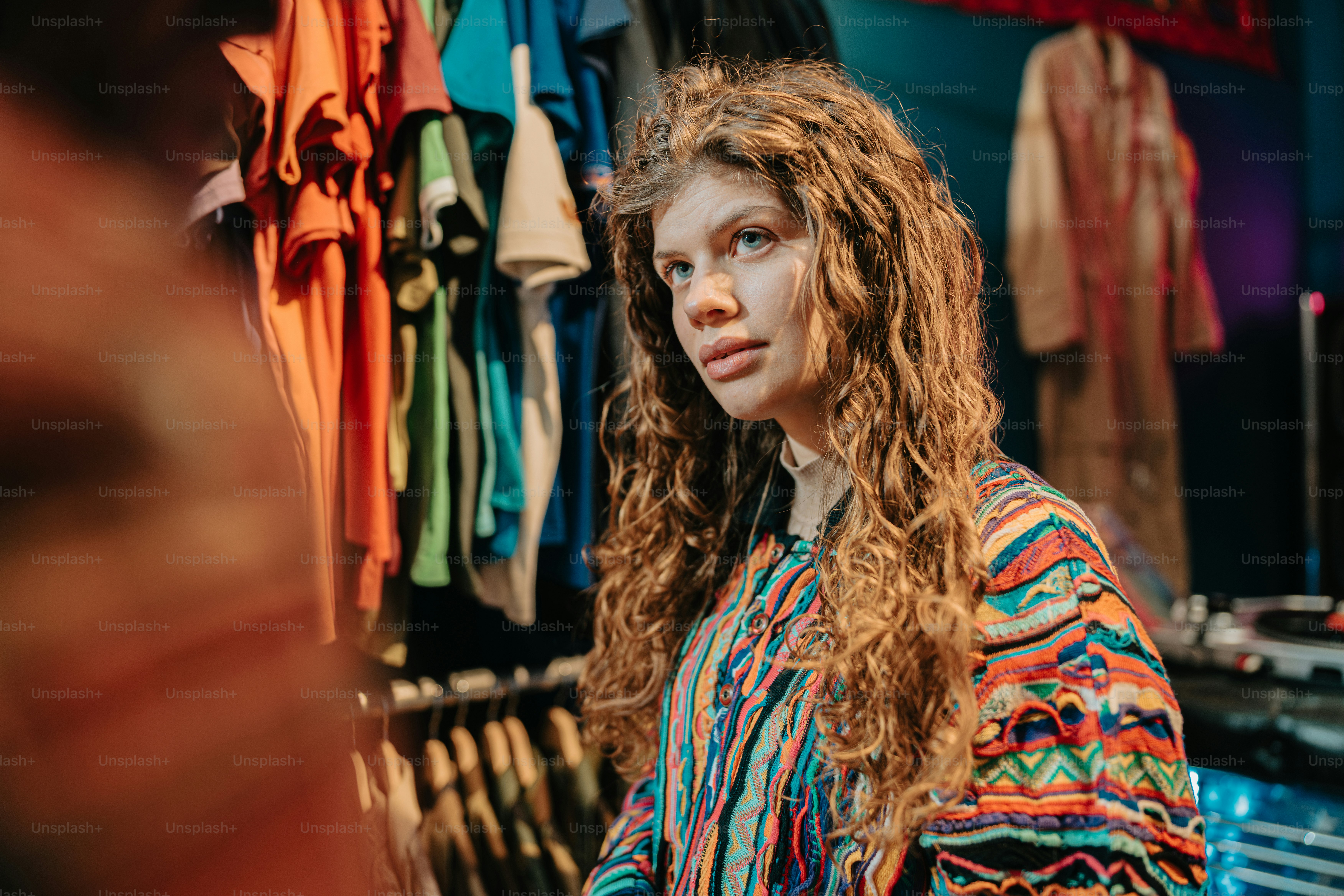 a woman standing in front of a rack of clothing