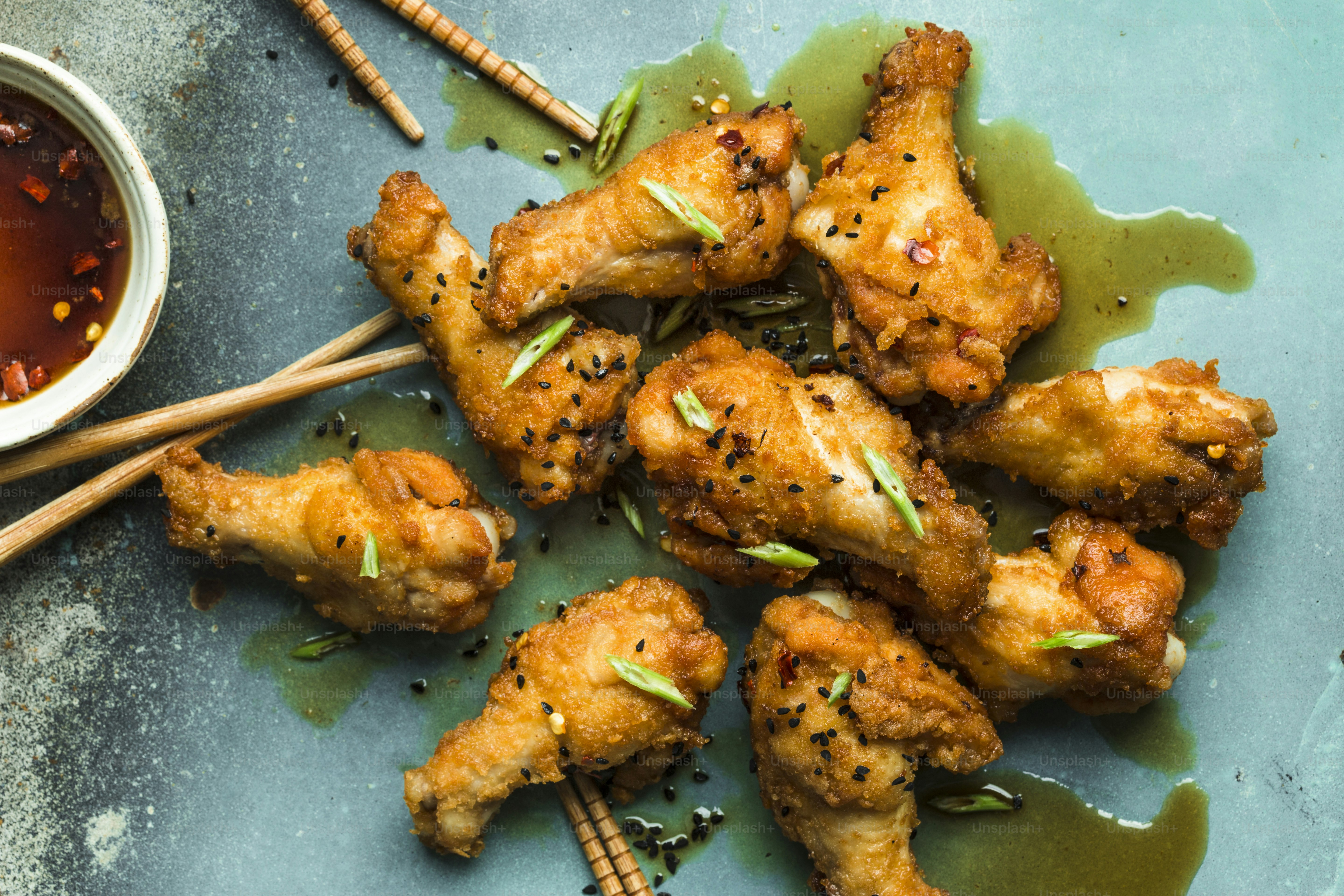 a blue plate topped with chicken wings next to a bowl of dipping sauce