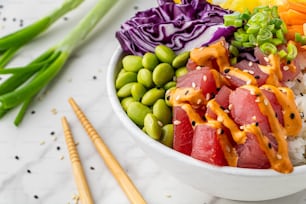 a bowl of sushi and vegetables with chopsticks