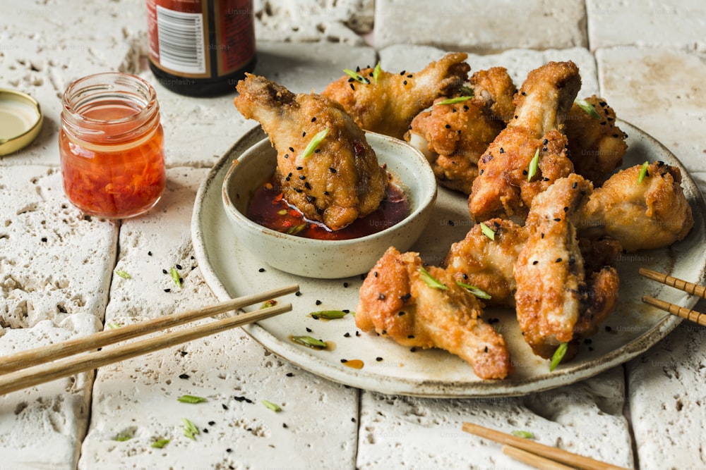 a plate of chicken wings with sauce and chopsticks