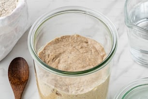 a jar of oatmeal next to a wooden spoon