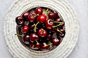 a bowl filled with cherries on top of a table
