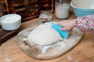 a person is kneading dough on a wooden board