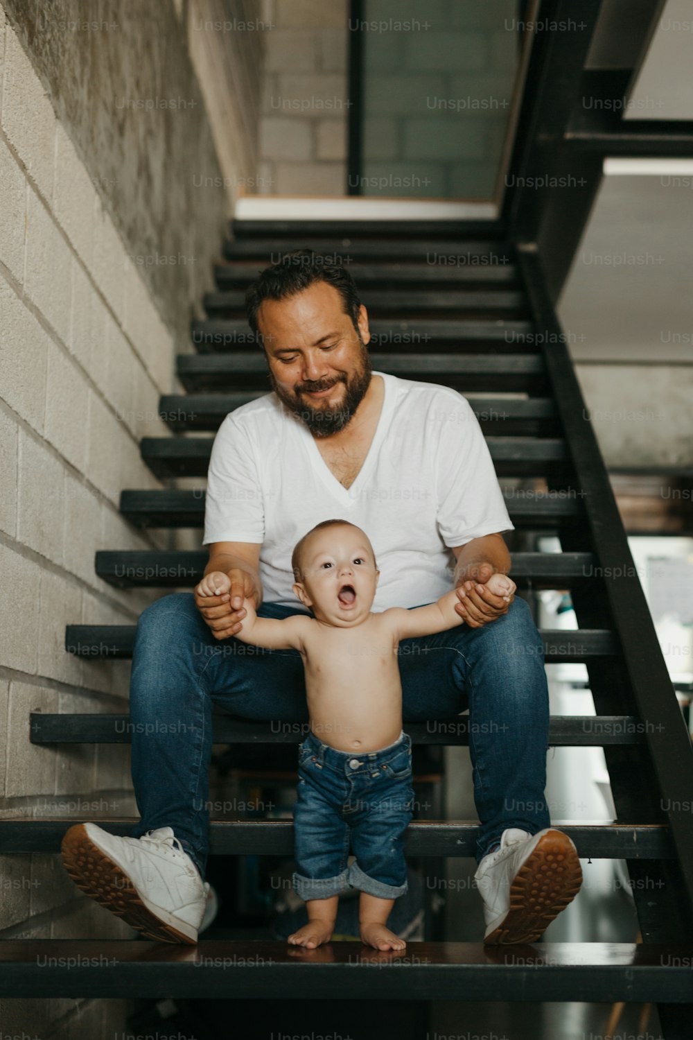 a man sitting on a stair case holding a baby