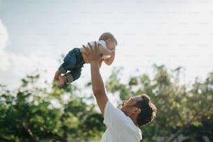 ein Mann, der ein Baby in die Luft hält