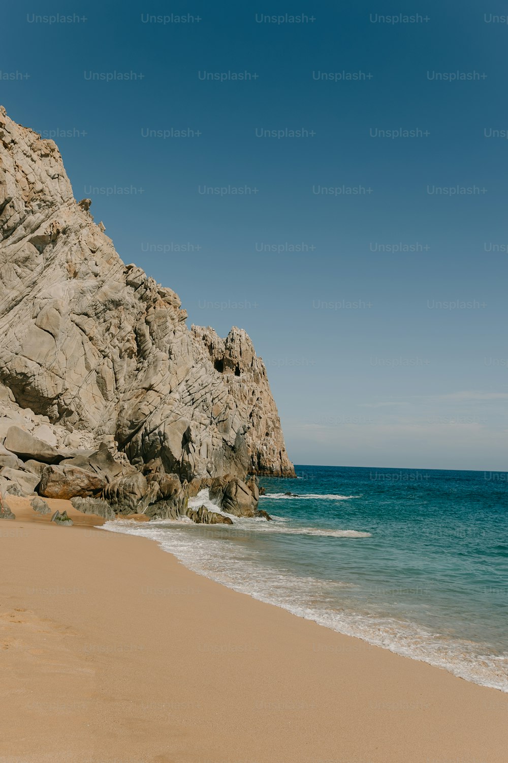 uma praia de areia ao lado de um penhasco rochoso