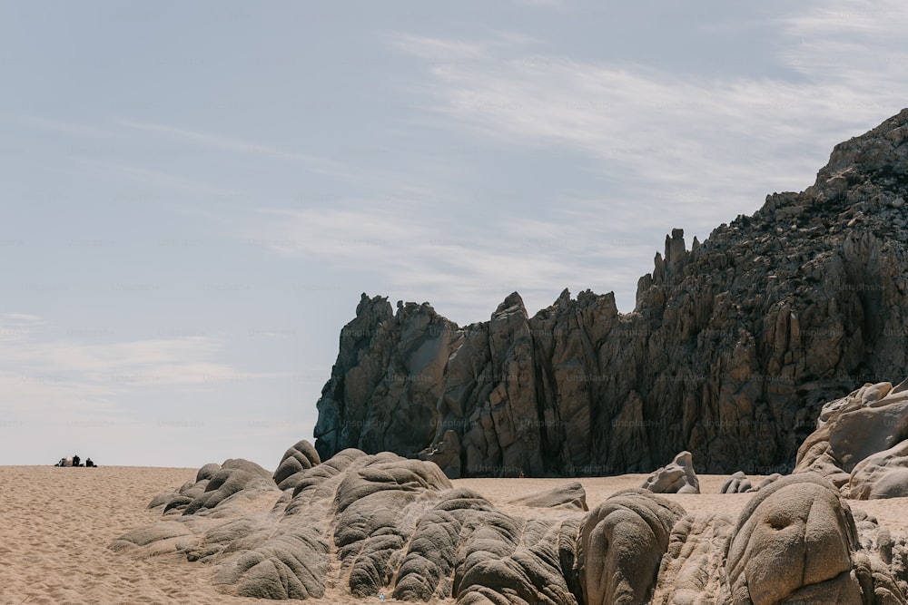 un grupo de grandes rocas sentadas en la parte superior de una playa de arena
