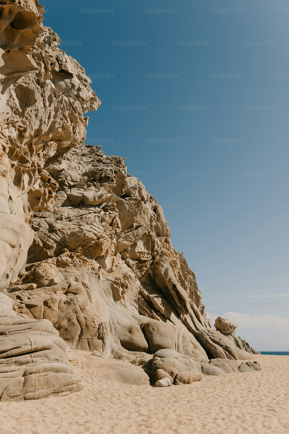uma praia de areia com uma grande formação rochosa em cima dela