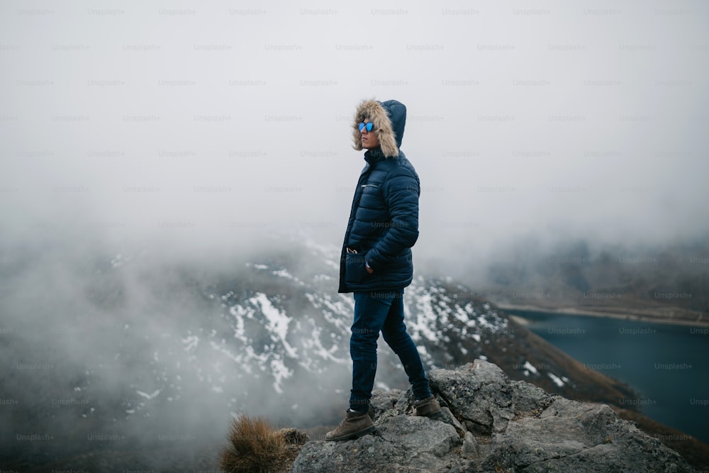 a man standing on top of a mountain next to a lake