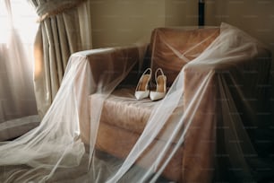 a pair of shoes sitting on top of a couch covered in a veil