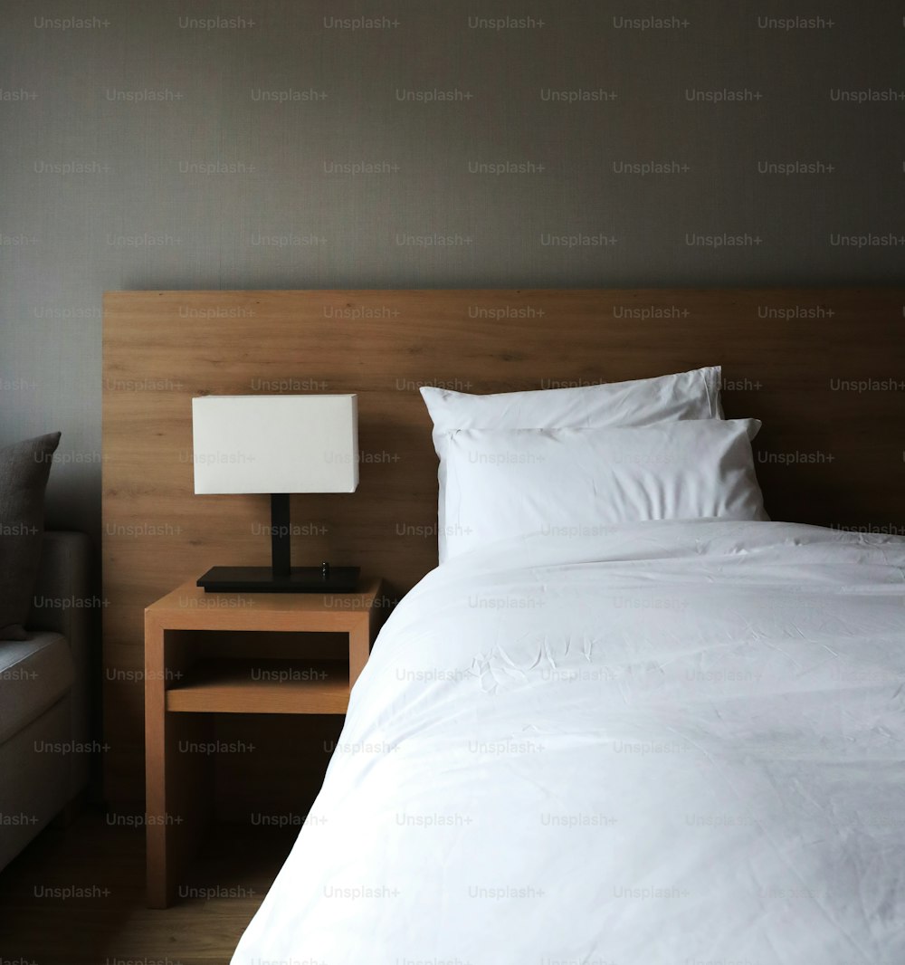 un letto con lenzuola bianche e cuscini in una stanza