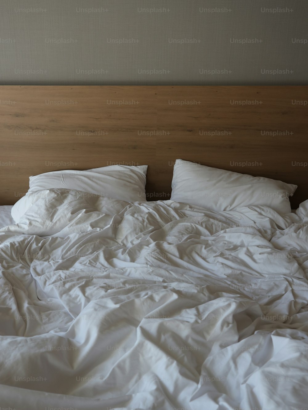 an unmade bed with white sheets and pillows