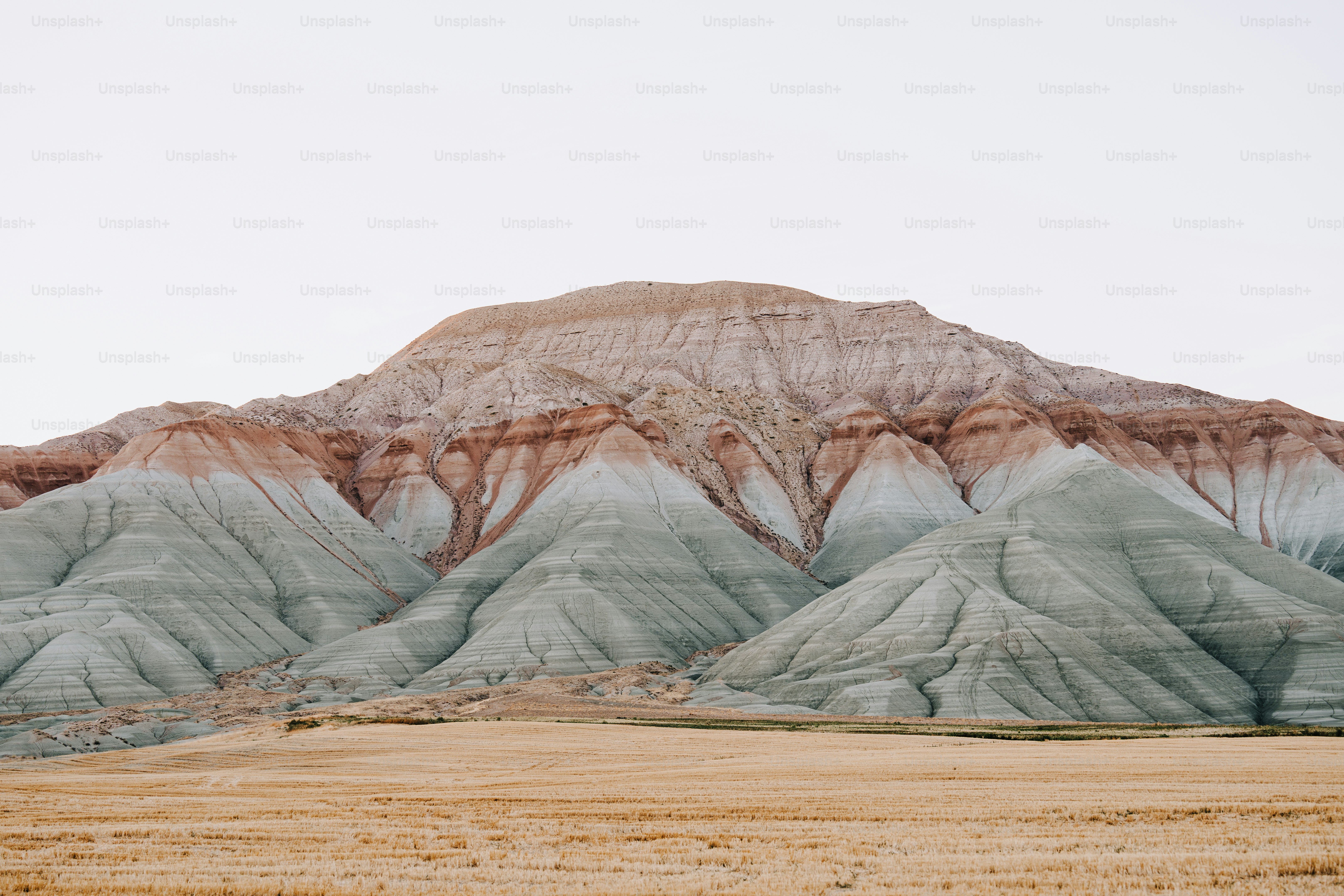a large mountain with a brown field in front of it