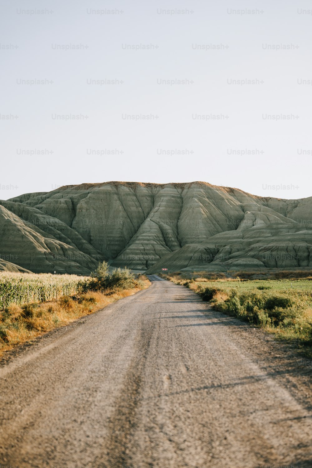 a dirt road with a hill in the background