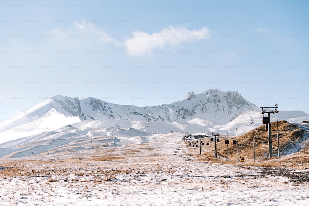 eine schneebedeckte Bergkette mit Telefonmasten im Vordergrund
