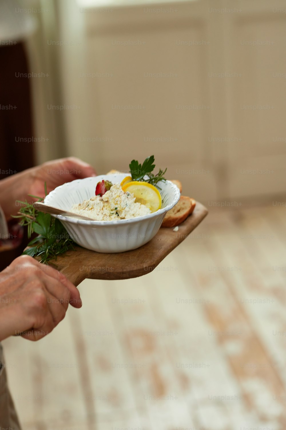 a person holding a bowl of food on a wooden board