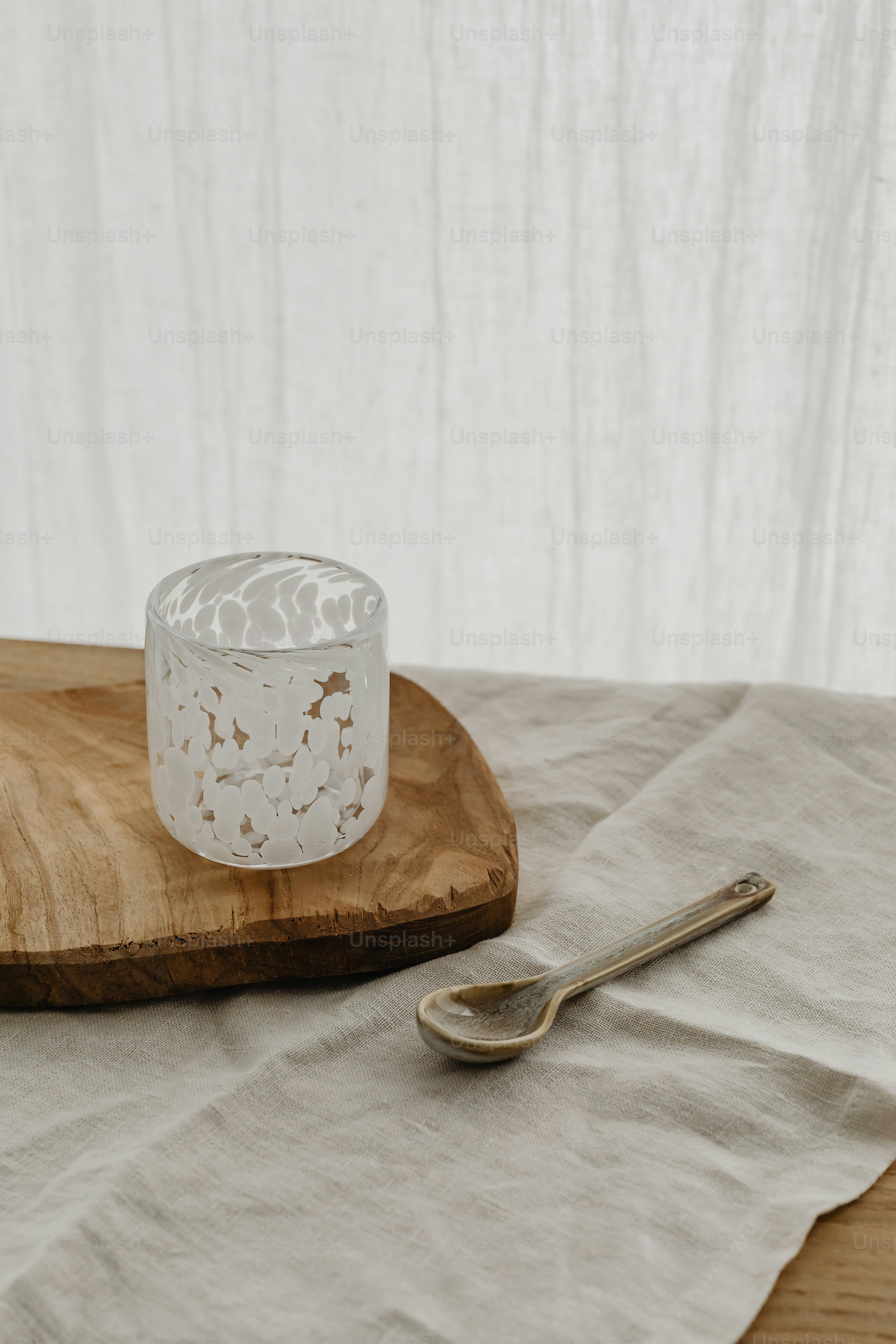 a wooden tray with a spoon and a glass on it