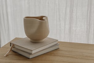 eine weiße Vase, die auf einem Stapel Bücher steht