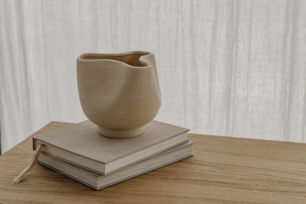 a white vase sitting on top of a stack of books