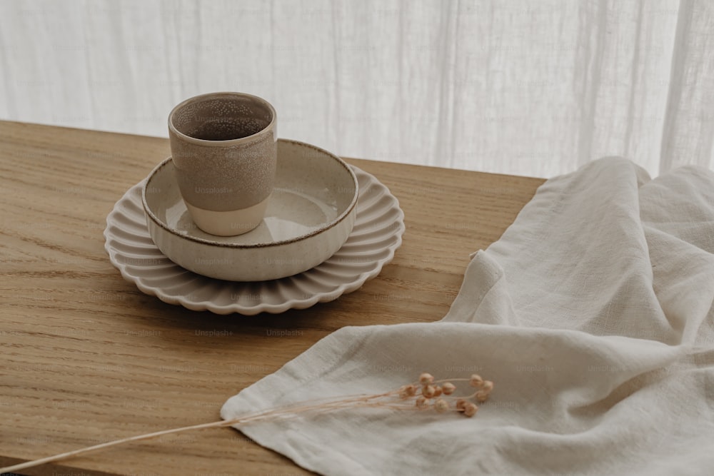 um copo e pires sentados em uma mesa de madeira