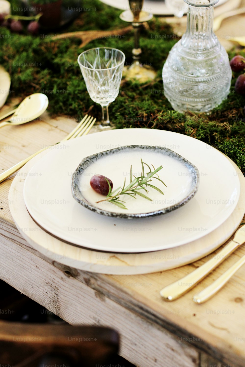a white plate topped with an olive on top of a wooden table