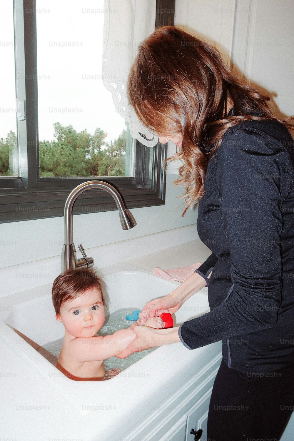 a woman washing a baby in a sink
