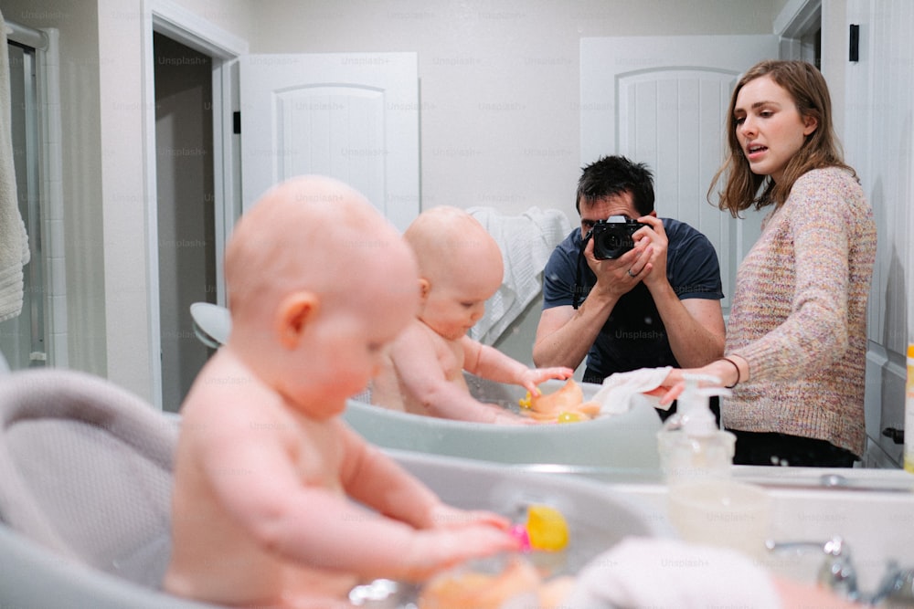 a man taking a picture of a baby in a bathtub