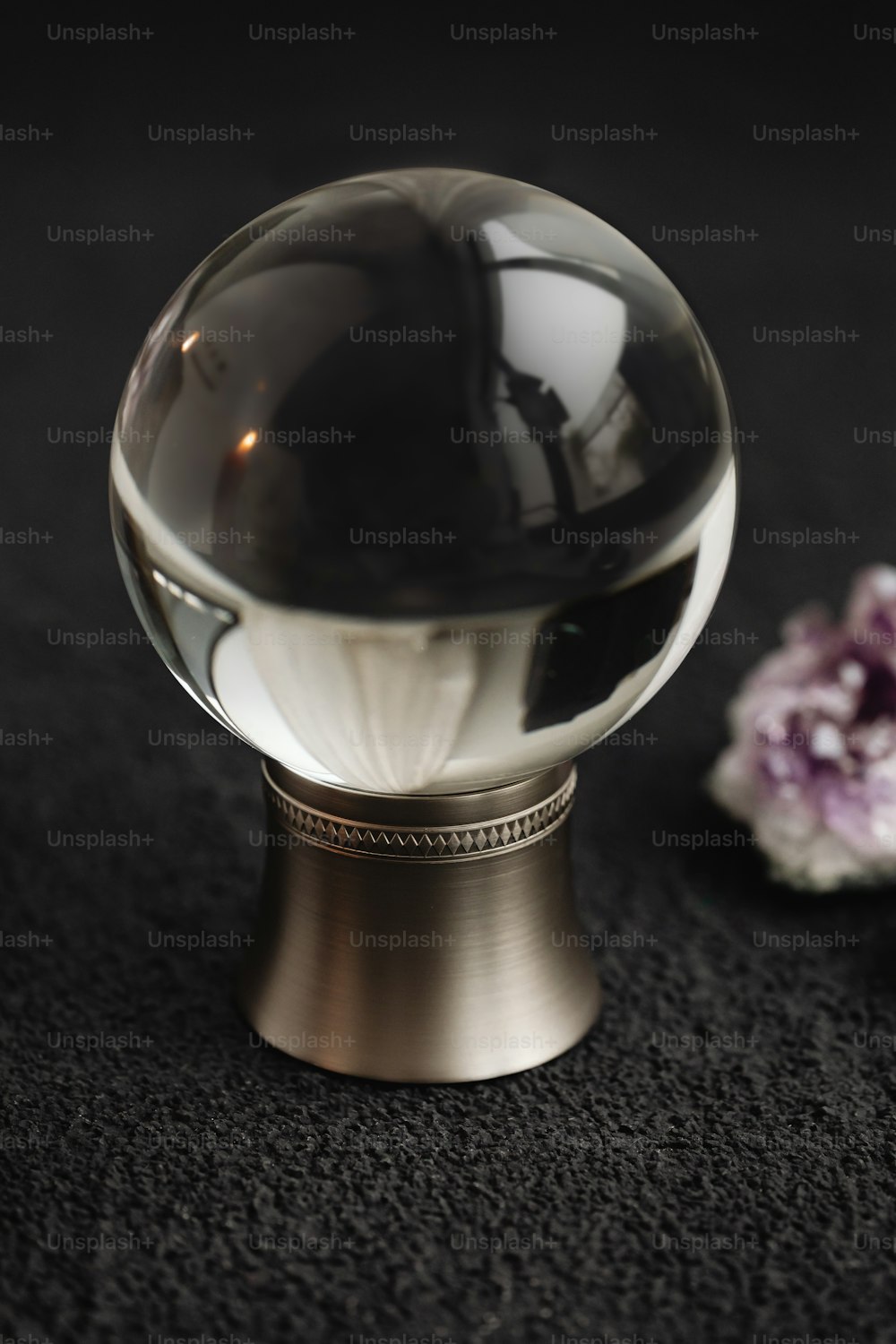 a glass ball on a metal stand next to a flower
