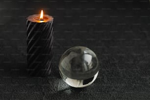 una bola de cristal sentada junto a una vela sobre una superficie negra