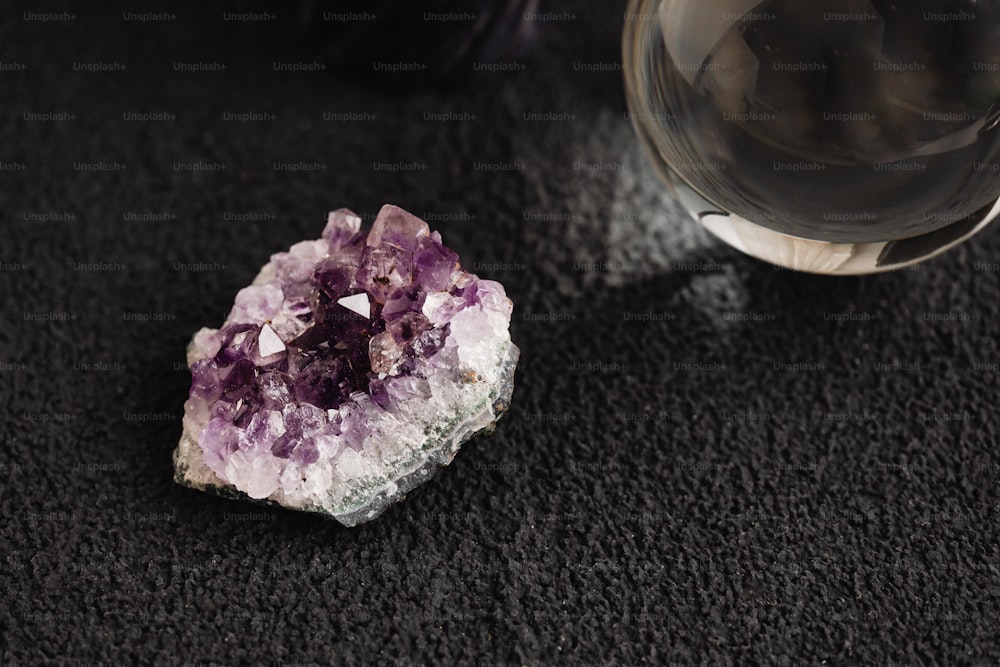 a purple rock sitting next to a glass of wine