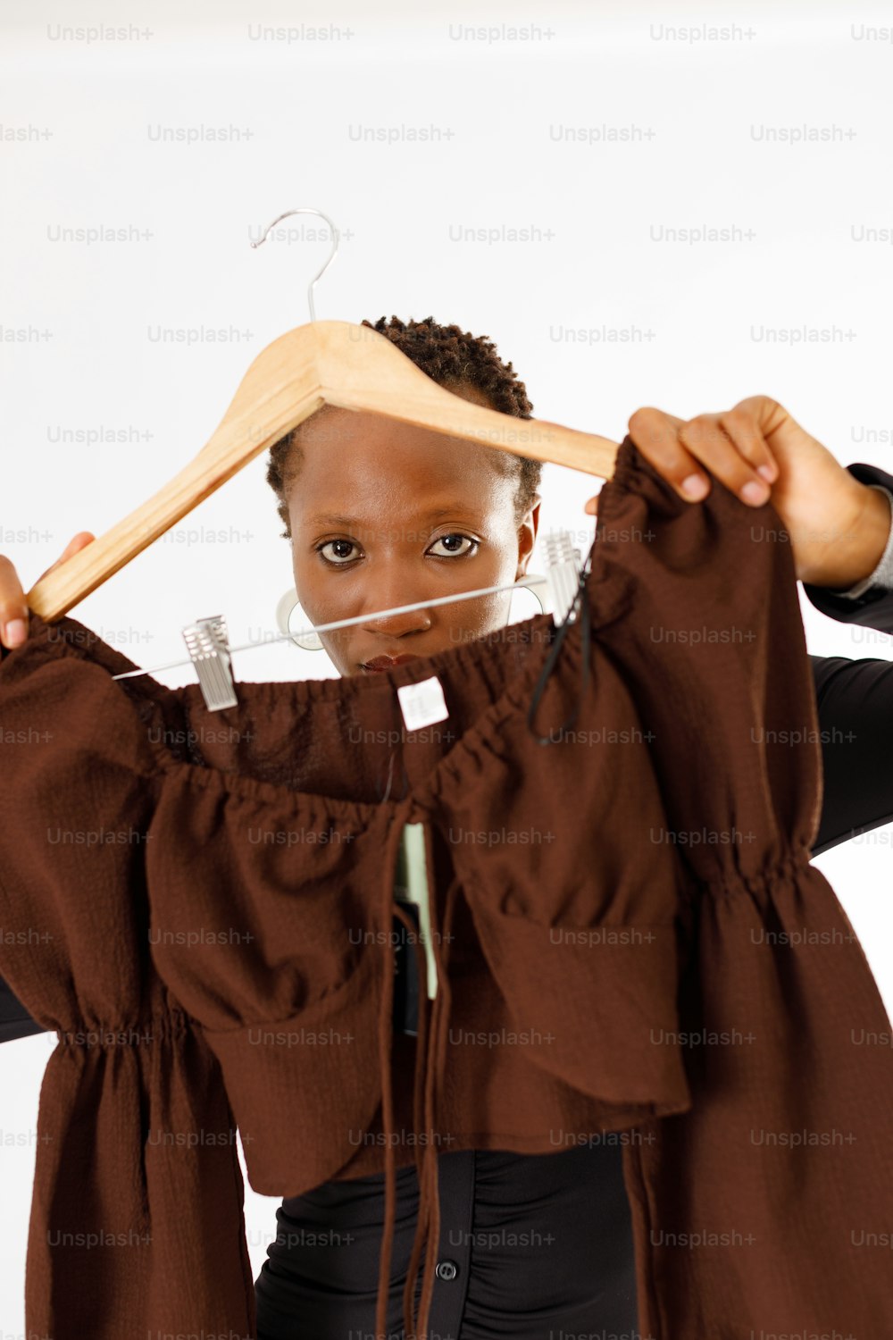 a woman holding a wooden hanger over her head