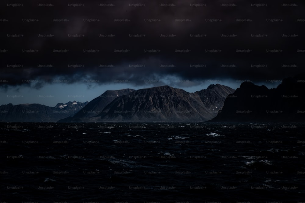 a dark sky over a mountain range in the ocean