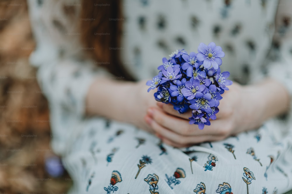 a close up of a person holding a bunch of flowers