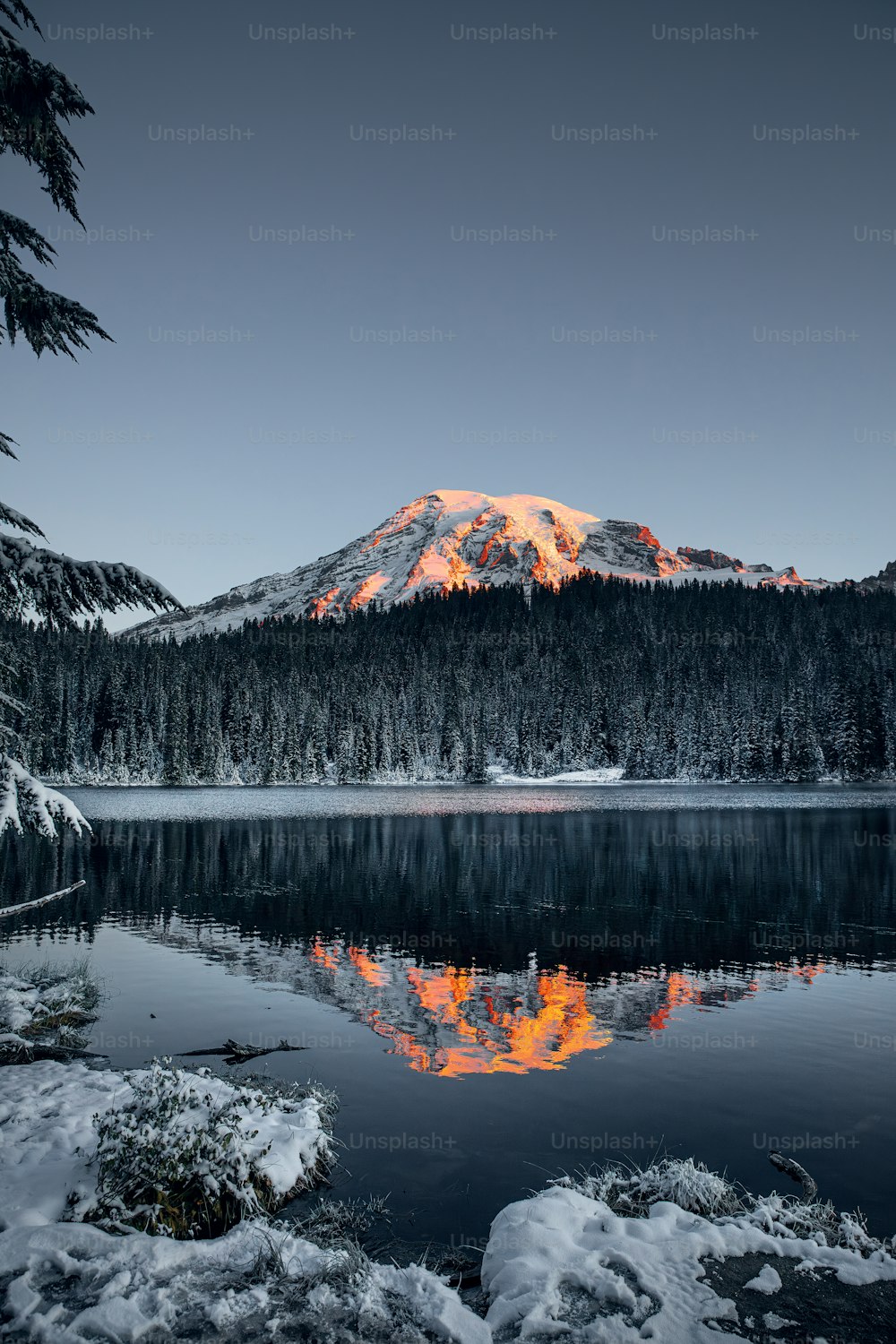 uma montanha é mostrada com um lago em primeiro plano