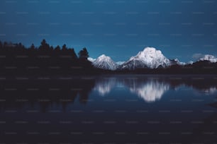 a mountain range is reflected in the still water of a lake