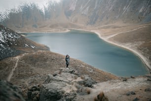 un hombre y una mujer de pie en la cima de una montaña junto a un lago