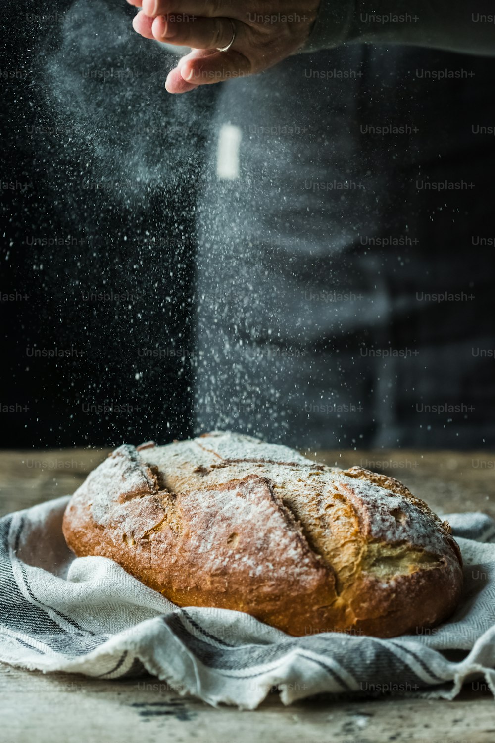 a person sprinkling sugar on a loaf of bread