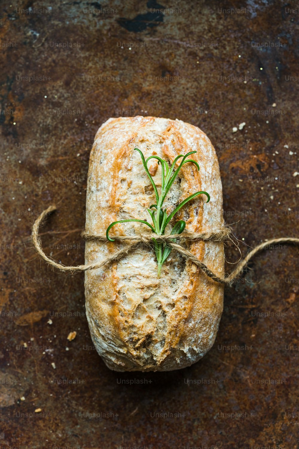 a loaf of bread with a sprig of rosemary tied to it