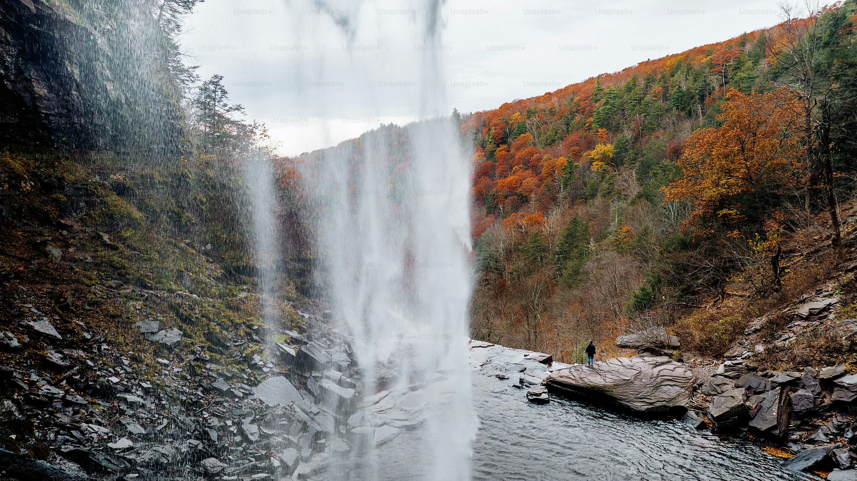 a waterfall with a person standing in the middle of it