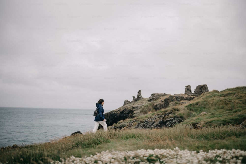 Una persona parada en la cima de una colina cerca del océano