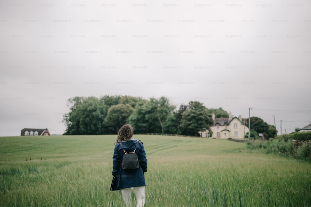 a woman with a backpack walking through a field