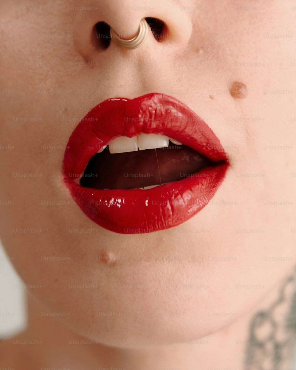 a woman with red lipstick and piercings on her lips