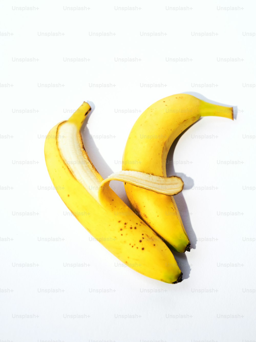um par de bananas sentado em cima de uma mesa branca