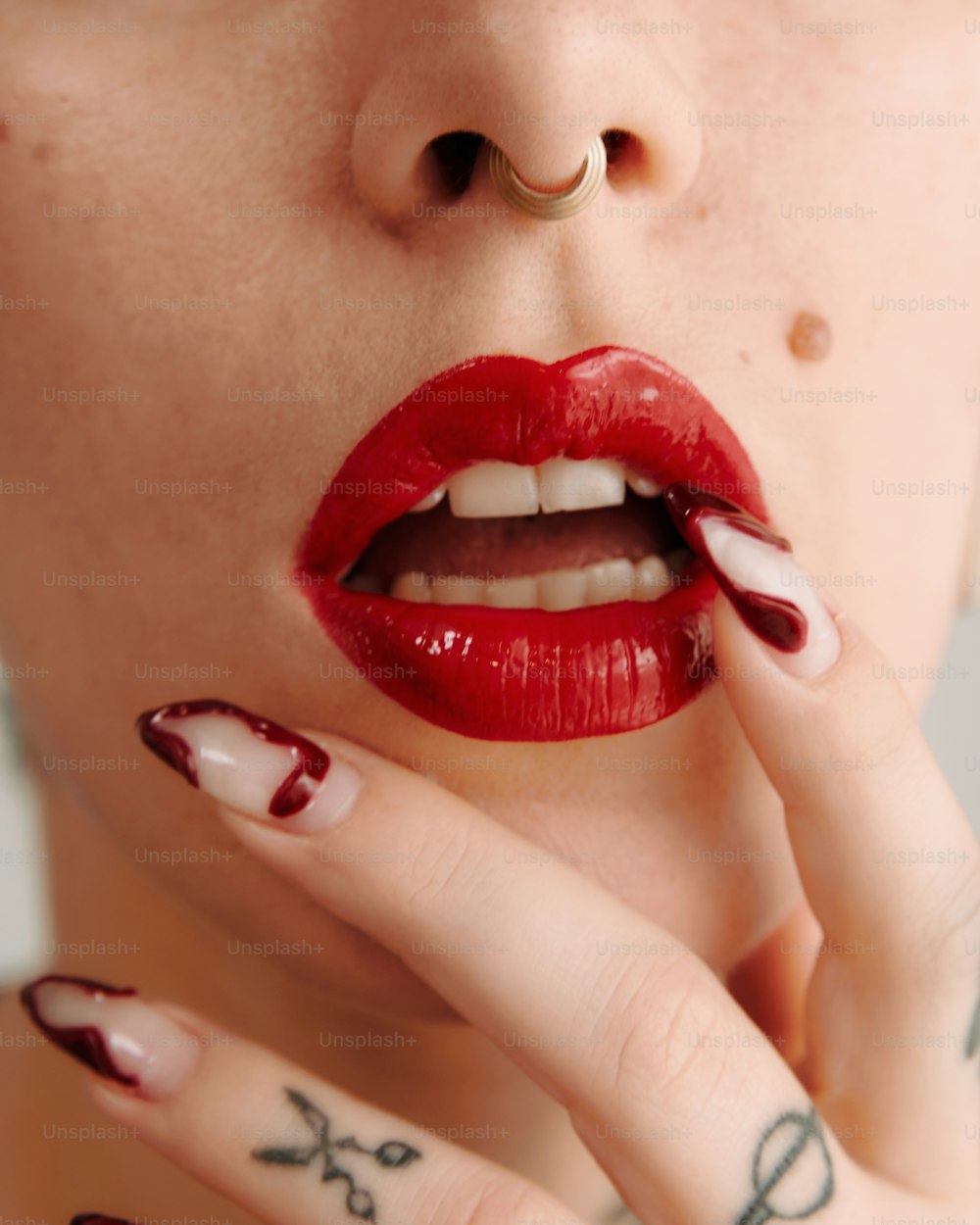 una mujer con esmalte de uñas rojo y blanco en los labios