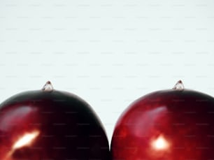 Eine Nahaufnahme von zwei roten Äpfeln mit weißem Hintergrund