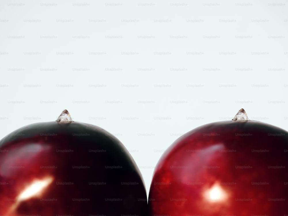 a close up of two red apples with a white background