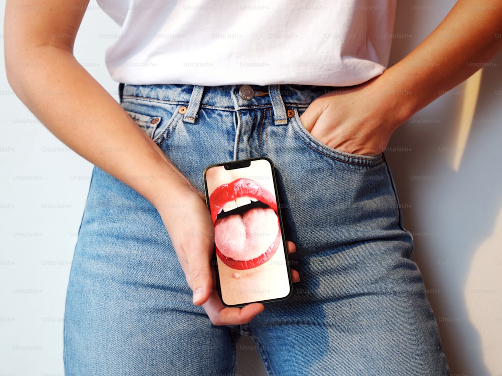 une personne tenant un téléphone portable sur lequel est posée une photo des lèvres d’une femme ;