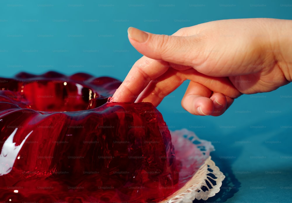 a person placing a piece of cake on top of a red cake